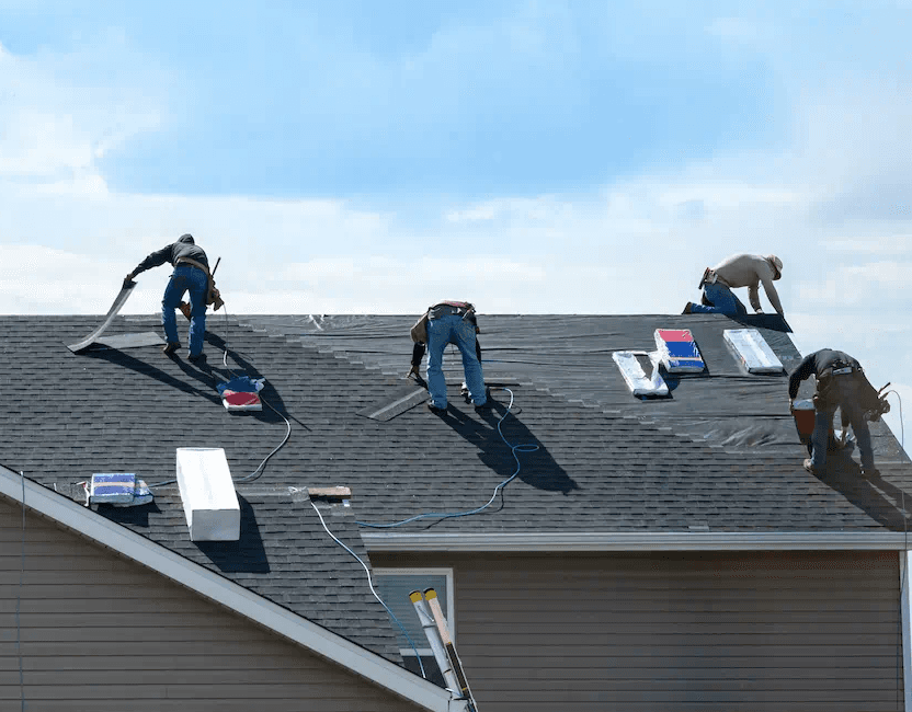 Roofing crew completing shingle courses on a residential roof
